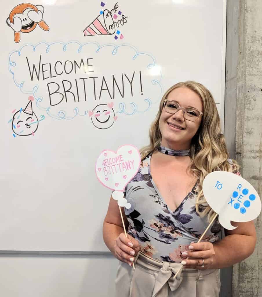 Brittany Tyson holding welcome signs at the REX office